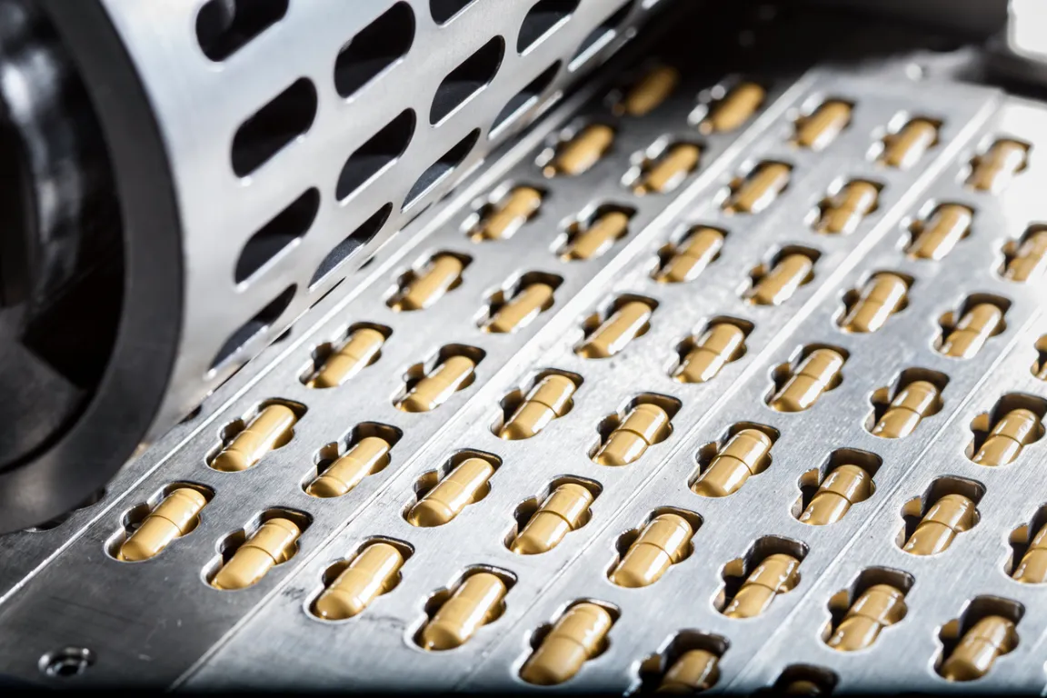 Capsules at a capsule press in a pharmaceutical manufacturing facility, closeup